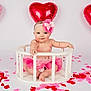 baby, child, tutu, headband, pink, balloon, heart_shaped, rose_petals, white_background, cute, smiling, sitting, wooden_enclosure, infant, studio_photo, valentines_day, decorations, pose, happy, celebration
