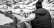 Bella participe au concours pour gagner de l'argent avec cette photo : black_and_white, person, dog, bench, mountains, snow, outdoor, hugging, back_view, nature, landscape, winter, coat, scenic, calm, companionship, animal, leisure, reflection, serene