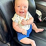baby, child, smiling, sitting, car_seat, black_leather, clothing, shorts, shirt, mickey_mouse, happy, cute, infant, skin, face, hand, foot, seat, interior, vehicle