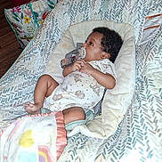 Charity is registered to the contest to win money with this photo: baby, baby_seat, baby_toy, blanket, child, clothing, colorful, comfort, cute, fabric, home, indoor, infant, pacifier, pattern, portrait, resting, shopping_bag, wood_floor, young_child