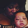 Charity is registered to the contest to win money with this photo: afro_hair, baby, casual, close_up, dark_background, dim_lighting, expression, face, holding, indoor, intimate, mother_and_child, person, portrait, selfie, sleepy_baby, striped_clothing, text_overlay, tiktok_watermark, woman
