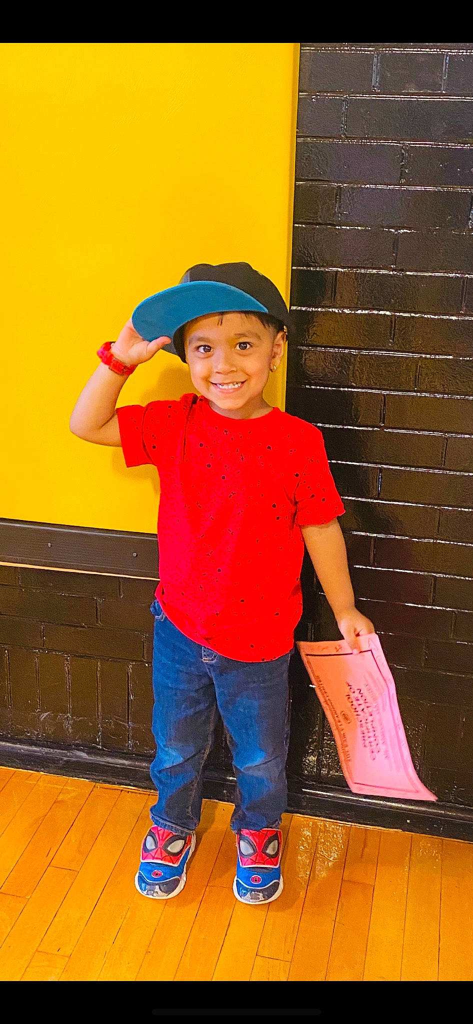 Marcus is registered to the contest to win money with this photo: baseball_cap, cap, child, denim, electric_blue, flooring, fun, happy, headwear, jeans, joy, leisure, magenta, outdoor_shoe, person, play, red, shoe, sleeve, smile