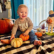 Bryden is registered to the contest to win money with this photo: toddler, child, pumpkin, halloween, tablecloth, smile, indoor, decorations, cute, happy, clothing, plant, toy, holiday, seasonal, face, jeans, barefoot, sitting, festive