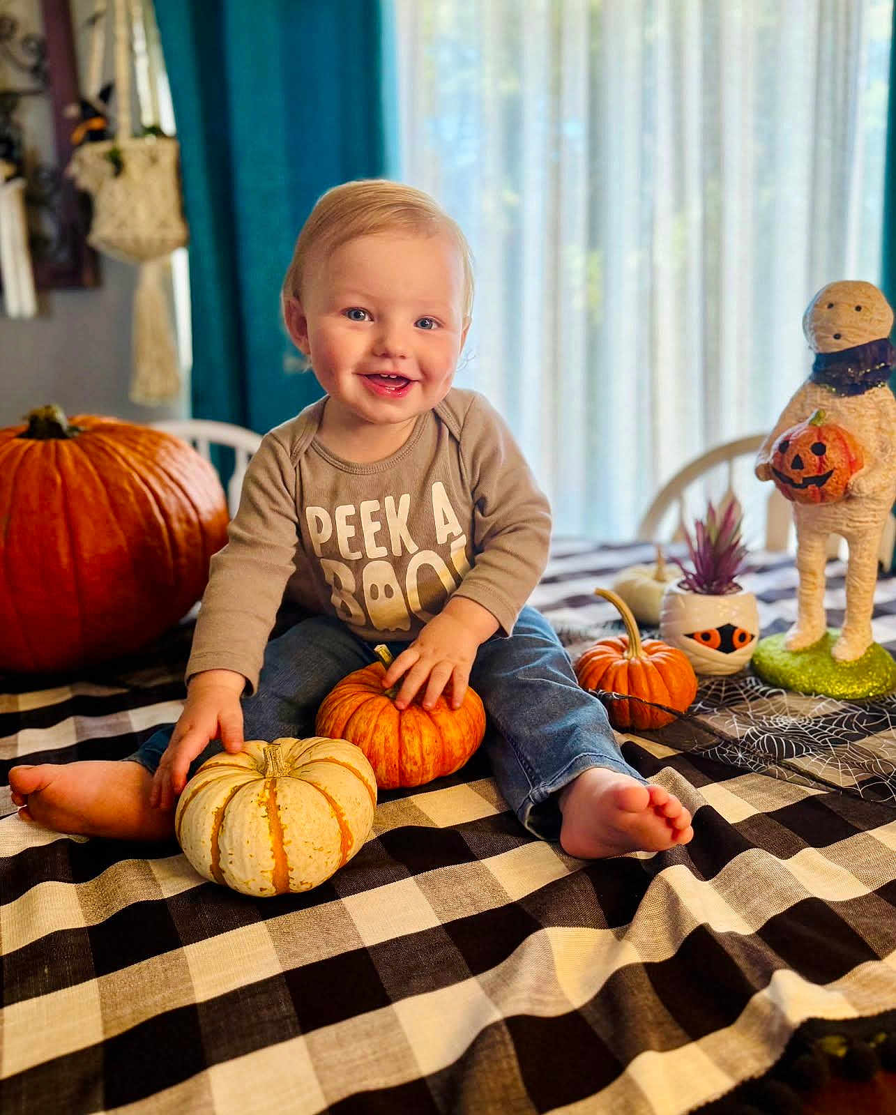 Bryden is registered to the contest to win money with this photo: toddler, child, pumpkin, halloween, tablecloth, smile, indoor, decorations, cute, happy, clothing, plant, toy, holiday, seasonal, face, jeans, barefoot, sitting, festive