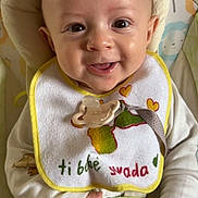 Issa a rejoint le concours — aidez-le/la à gagner de superbes lots ! baby, smiling, bib, pacifier, child, infant, cute, happy, clothing, hand, face, sitting, indoor, cushion, toy, animal_print, portrait, young_child, closeup, soft_lighting