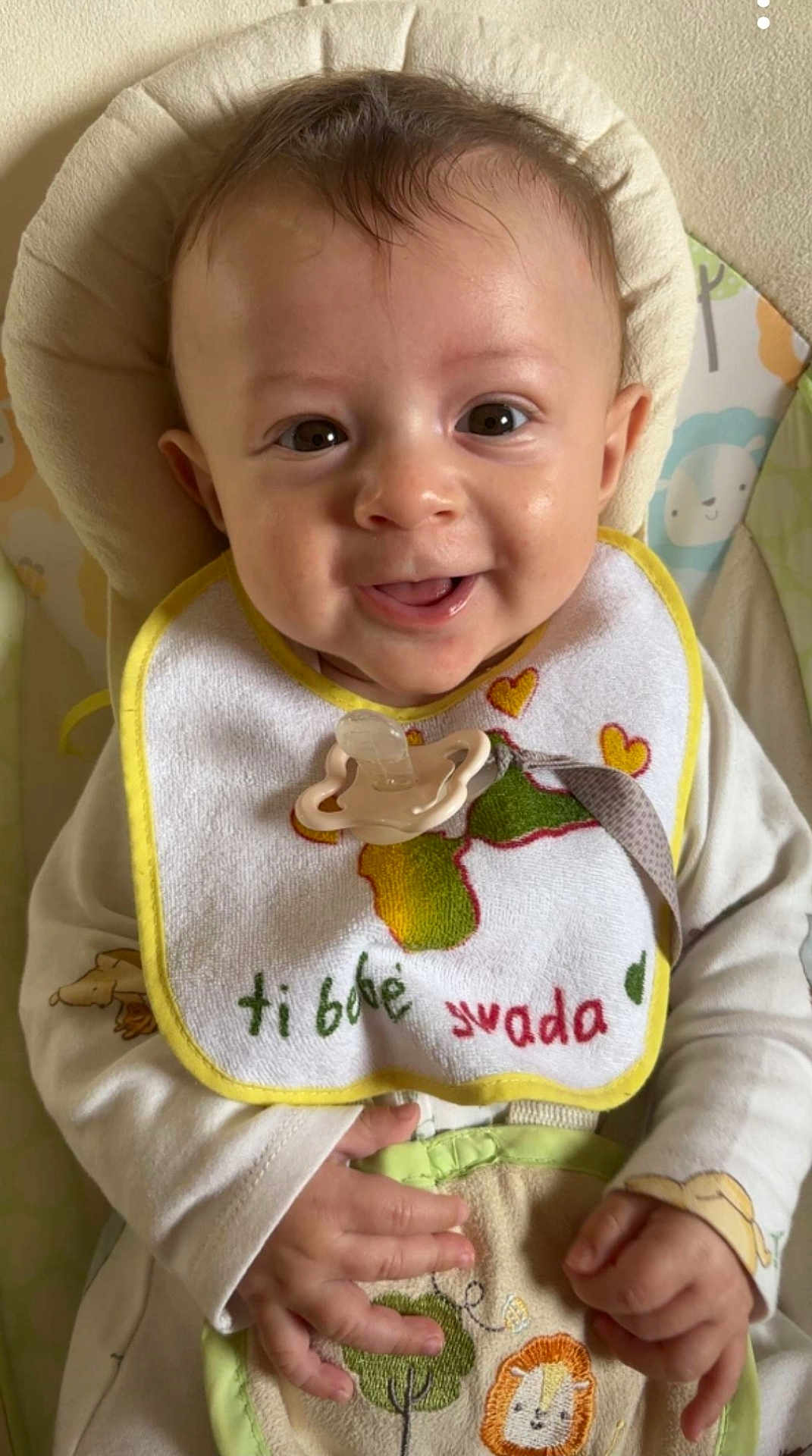 Issa a rejoint le concours — aidez-le/la à gagner de superbes lots ! baby, smiling, bib, pacifier, child, infant, cute, happy, clothing, hand, face, sitting, indoor, cushion, toy, animal_print, portrait, young_child, closeup, soft_lighting