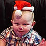 baby, child, santa_hat, plaid_shirt, cute, smiling, indoor, portrait, face, headwear, holiday, christmas, young_child, person, infant, candid, seated, hand, expression, background