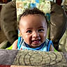 baby, child, smiling, curly_hair, high_chair, indoor, portrait, happy, cute, infant, person, face, clothing, blue, seat, expression, young, cheerful, skin, head