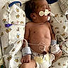 newborn, baby, infant, hospital, medical_equipment, incubator, bassinet, sleeping, face, portrait, diaper, monitoring, tubes, nasal_cannula, electrodes, hospital_bedding, blanket, healthcare, premature_infant, indoors