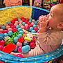 Luna joined the competition — help win amazing prizes! baby, ball_pit, plastic_balls, toy, child, indoor, colorful, play, cute, infant, sitting, clothing, face, hand, expression, background, soft_lighting, room, floor, fun
