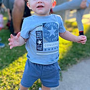Ryder is registered to the contest to win money with this photo: toddler, child, boy, standing, outdoor, sunlight, blue_eyes, shorts, tshirt, sneakers, grass, sidewalk, smile, happy, converse, person, casual_clothing, daylight, blurred_background, playful