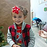 Marquis is registered to the contest to win money with this photo: child, christmas_tree, clothing, curly_hair, cute, decor, floor, furniture, hand, happy, holiday, indoor, person, plaid_jacket, playful, red_bow, smiling, toddler, toy, wall