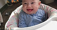 Esme joined the competition — help win amazing prizes! baby, high_chair, smiling, happy, tongue_out, blue_clothing, indoor, person, floor, furniture, home, child, infant, seat, playful, cute, expression, human, babysuit, joy