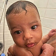 Yasahn is registered to the contest to win money with this photo: baby, child, bath, wet_skin, curly_hair, face, large_eyes, hand, arm, skin, shower, tile_wall, bathroom, cute, infant, person, water_droplets, holding, closeup, expression