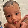 baby, child, bath, wet_skin, curly_hair, face, large_eyes, hand, arm, skin, shower, tile_wall, bathroom, cute, infant, person, water_droplets, holding, closeup, expression