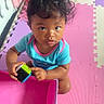 toddler, child, curly_hair, toy, block, colorful, play_mat, pink, purple, blue_shirt, indoor, looking_up, person, cute, baby, hands, sitting, floor, expression, young_child