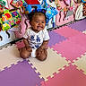Ellayah is registered to the contest to win money with this photo: baby, child, smiling, sitting, indoors, colorful, toys, books, playmat, hair_bows, happy, cute, person, floor, play_area, clothing, infant, early_childhood, development, fun