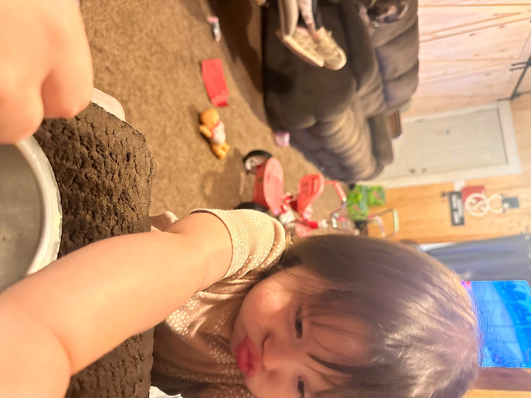 Vivianna is registered to the contest to win money with this photo: arm, black_hair, child, ear, finger, flooring, fun, hairstyle, happy, human_leg, leisure, long_hair, nail, neck, organ, person, room, soil, thigh, toddler