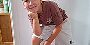 Eladio participe au concours pour gagner de l'argent avec cette photo : boy, cabinet, casual_clothing, child, floor, furniture, happy, home, indoor, light_switch, person, portrait, pose, shelf, shorts, smile, socks, tshirt, wall, wood_floor