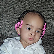 Harlow is registered to the contest to win money with this photo: braids, child, clothing, cute, expression, eyes, face, hair, head_and_shoulders, indoor, mouth, nose, person, pink_beads, portrait, sitting, skin, toddler, white_hoodie, young