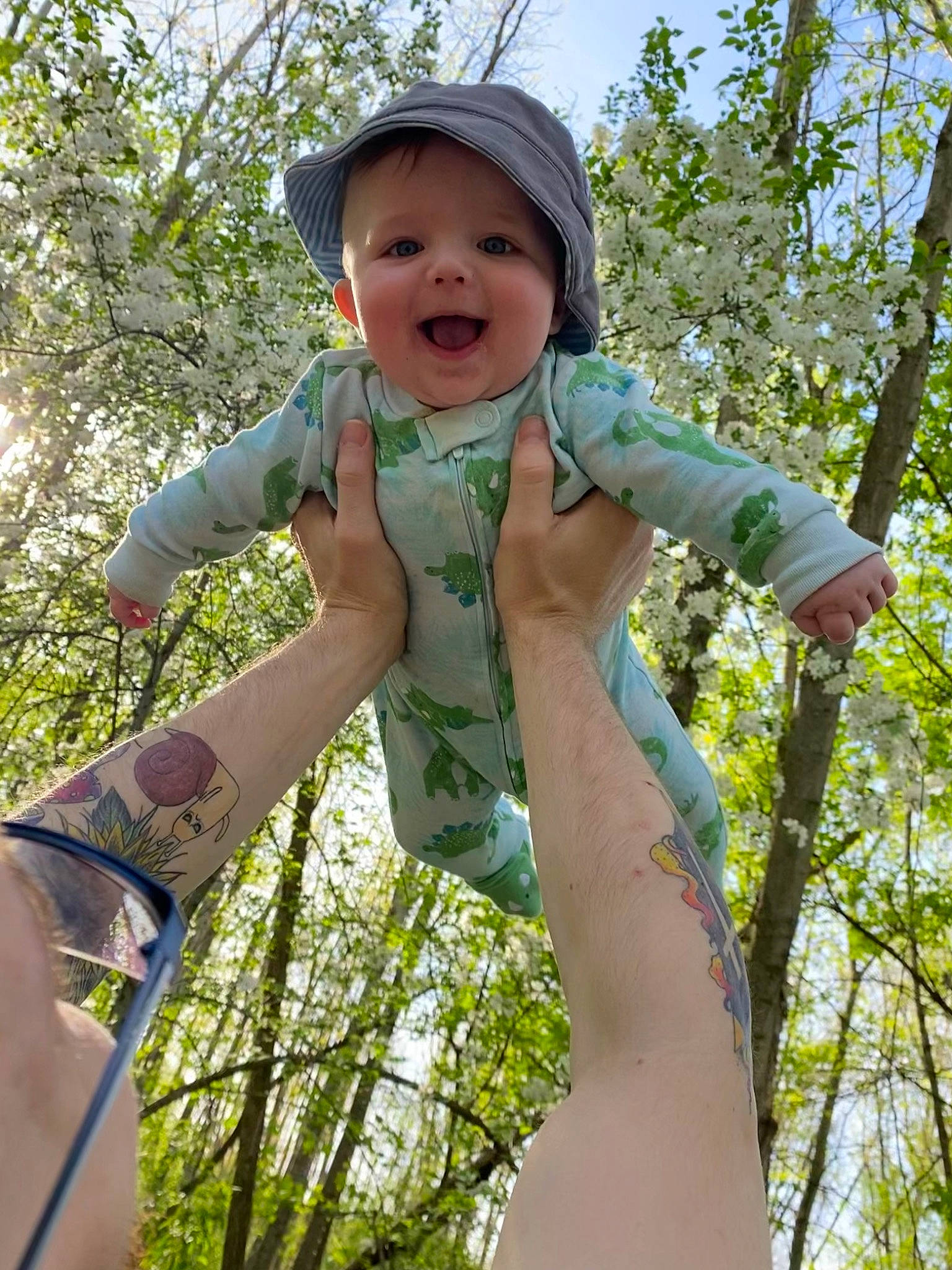 Liam is registered to the contest to win money with this photo: arm, baby_toddler_clothing, chest, child, face, finger, fun, gesture, grass, hand, happy, headwear, leisure, people_in_nature, person, plant, shoulder, sky, smile, toddler