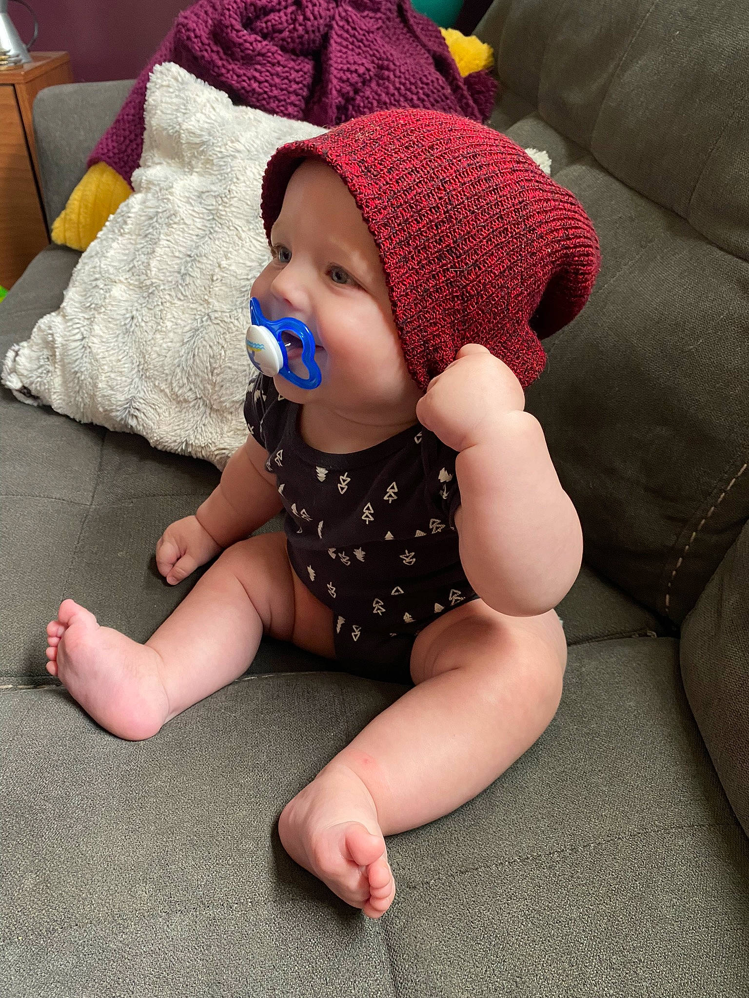 Liam joined the competition — help win amazing prizes! baby, baby_toddler_clothing, beanie, cap, carmine, child, comfort, couch, flooring, foot, fun, headwear, human_leg, knee, lap, pattern, person, sitting, sleeve, sock