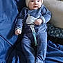 baby, infant, child, beanie, hat, onesie, whale_print, pacifier_clip, blanket, couch, sofa, pillow, blue_color, clothing, face, eyes, hands, feet, indoor, portrait