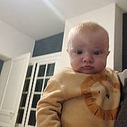 Aksel participe au concours pour gagner de l'argent avec cette photo : baby, infant, child, face, eyes, cheeks, onesie, lion_print, long_sleeve, arm, hand, holding, indoor, window, door, wall, hair, portrait, blurred, low_light