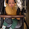 Kiari is registered to the contest to win money with this photo: baby, child, stroller, hoodie, fuzzy_clothing, green_pants, socks, indoor, portrait, face, expression, seated, comfort, warm_clothing, curious, number_overlay, black_stroller, hands, cushion, cozy