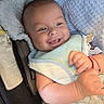 baby, smiling, bib, bottle, blanket, infant, happy, cute, chubby_cheeks, face, person, indoor, closeup, newborn, child, soft_lighting, comfort, car_seat, red_bracelet, cozy