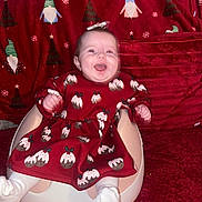 Lizzie joined the competition — help win amazing prizes! baby, baby_seat, blanket, child, christmas_pudding_pattern, christmas_tree_pattern, cozy, cute, festive, gnome_pattern, happy, holiday_theme, indoor, infant, portrait, red_dress, sitting, smiling, white_socks, young_child