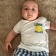 élio a rejoint le concours — aidez-le/la à gagner de superbes lots ! baby, infant, child, tshirt, lemon, blue_shorts, checkered, carpet, floor, lying_down, eyes_open, cute, casual_clothing, indoor, skin, hand, portrait, expression, young, person