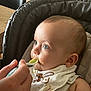 baby, bib, blue_eyes, bunny, care, child, close_up, cute, feeding, feeding_time, food, hand, high_chair, indoor, infant, messy_face, person, soft_lighting, spoon, textile