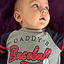 élio a rejoint le concours — aidez-le/la à gagner de superbes lots ! baby, baseball, blanket, blue_eyes, casual, child, clothing, cute, expression, face, head, indoors, infant, lying_down, portrait, purple, shirt, skin, text_on_clothing, young_child