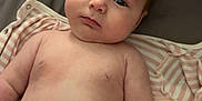 Poppy is registered to the contest to win money with this photo: baby, infant, diaper, bed, blanket, clothing, lying_down, indoors, skin, face, arms, torso, expression, soft, sleepwear, comfort, newborn, cute, chubby, child