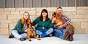 Georgia is registered to the contest to win money with this photo: boots, casual_clothing, collar, concrete_floor, dog, family, group, happy, jeans, leash, outdoor, people, pet, plaid_shirt, portrait, sitting, smiling, stone_wall, sweater, tongue_out