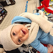 Otilia participe au concours pour gagner de l'argent avec cette photo : aisle, baby, candid, child_in_cart, closeup, coat, eyes, face, floor_tiles, groceries, happy, hat, mittens, portrait, shelves, shopping_cart, smile, supermarket, toddler, winter_clothing