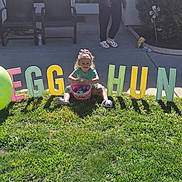 Astrid is registered to the contest to win money with this photo: child, toddler, grass, basket, eggs, egg_balloon, letters, egg_hunt, outdoor, sunlight, shadow, greenery, sidewalk, patio_chairs, person, playful, fun, spring, holiday, celebration