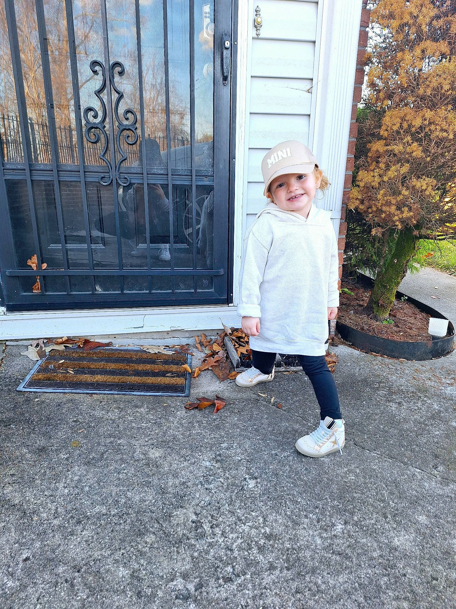 Charli is registered to the contest to win money with this photo: asphalt, boot, carnivore, companion_dog, fence, flooring, grass, headwear, joy, leaf, leisure, metal, person, plant, road_surface, shadow, sidewalk, sitting, sneakers, stairs