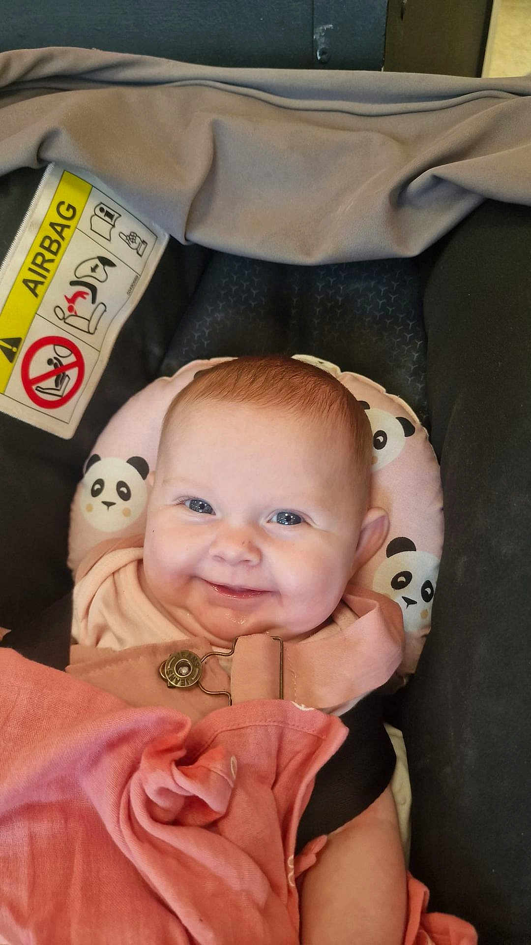 Isla-May is registered to the contest to win money with this photo: baby, smiling, face, infant, car_seat, panda_pattern, blanket, clothing, pink, head, seatbelt, child, indoors, cute, happy, safety, portrait, baby_bib, soft_toys, closeup