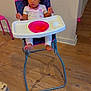 child, toddler, high_chair, pink, blue, plate, watermelon, food, pajamas, curly_hair, indoor, wooden_floor, white_wall, feet, hands, expression, person, furniture, table, seat