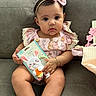 adorable, baby, bow, bracelet, child, couch, cute, floral_pattern, girl, headband, indoor, infant, person, pink_clothing, portrait, sitting, sock, soft_lighting, teether, toy
