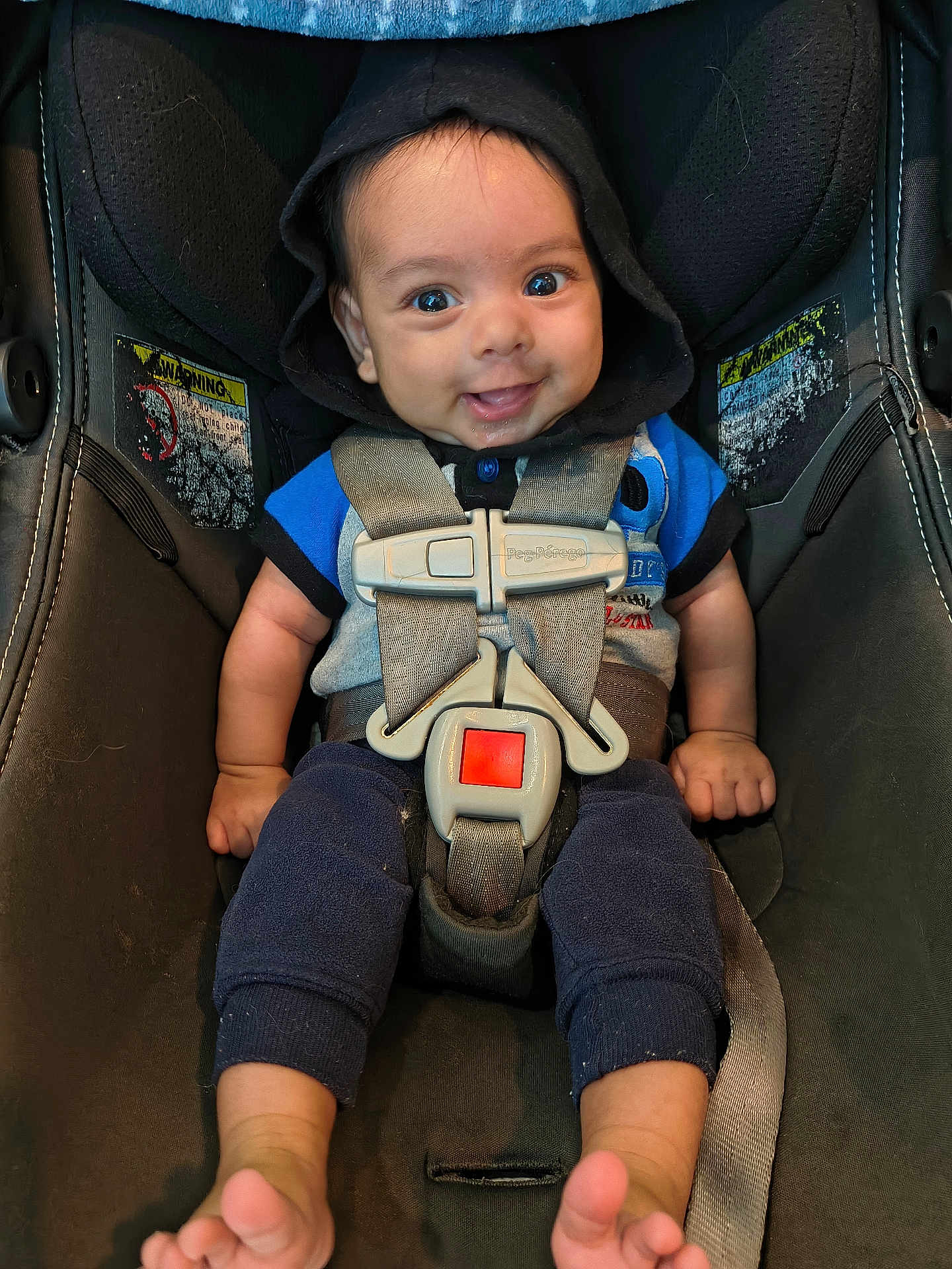 Malakai is registered to the contest to win money with this photo: baby, infant, car_seat, child, smile, hoodie, seatbelt, safety, cute, blue_clothing, happy, person, foot, hand, straps, seat, indoors, portrait, young_child, looking_at_camera