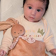 Ana participe au concours pour gagner de l'argent avec cette photo : baby, child, face, toy, stuffed_animal, bunny, clothing, sitting, indoor, portrait, cute, soft_toy, infant, expression, looking_at_camera, pink, beige, floral_pattern, blanket, person