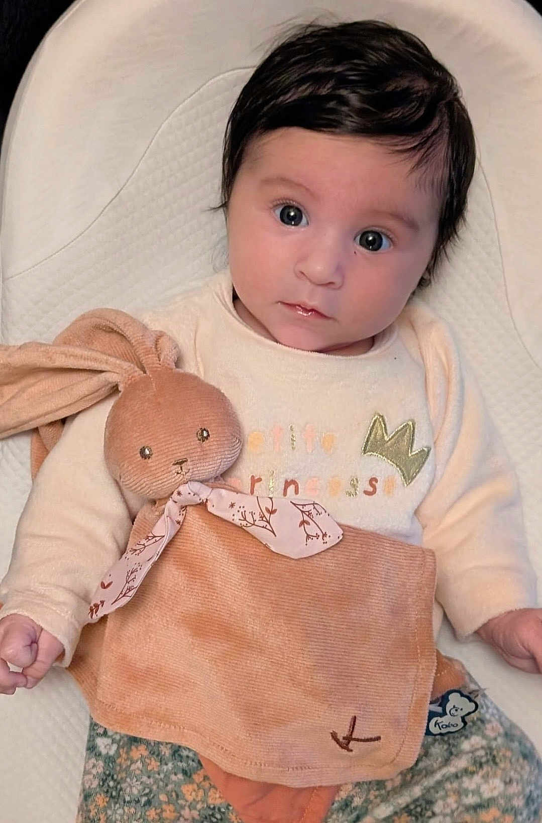 Ana participe au concours pour gagner de l'argent avec cette photo : baby, child, face, toy, stuffed_animal, bunny, clothing, sitting, indoor, portrait, cute, soft_toy, infant, expression, looking_at_camera, pink, beige, floral_pattern, blanket, person