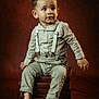 toddler, child, boy, suspenders, barefoot, books, stack, portrait, studio, brown_background, curious, clothing, sitting, indoors, young_child, cute, fashion, expression, person, photography