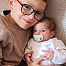 Nina a rejoint le concours — aidez-le/la à gagner de superbes lots ! child, baby, glasses, pacifier, couch, sibling, hug, smile, indoor, cozy, love, family, portrait, casual_clothing, candid, comfort, relaxation, toddler, infant, home