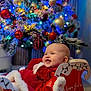 baby, child, christmas_tree, ornaments, lights, holiday, sleigh, red_clothing, smiling, festive, indoor, decorations, happy, face, celebration, winter, cute, seasonal, christmas, infant