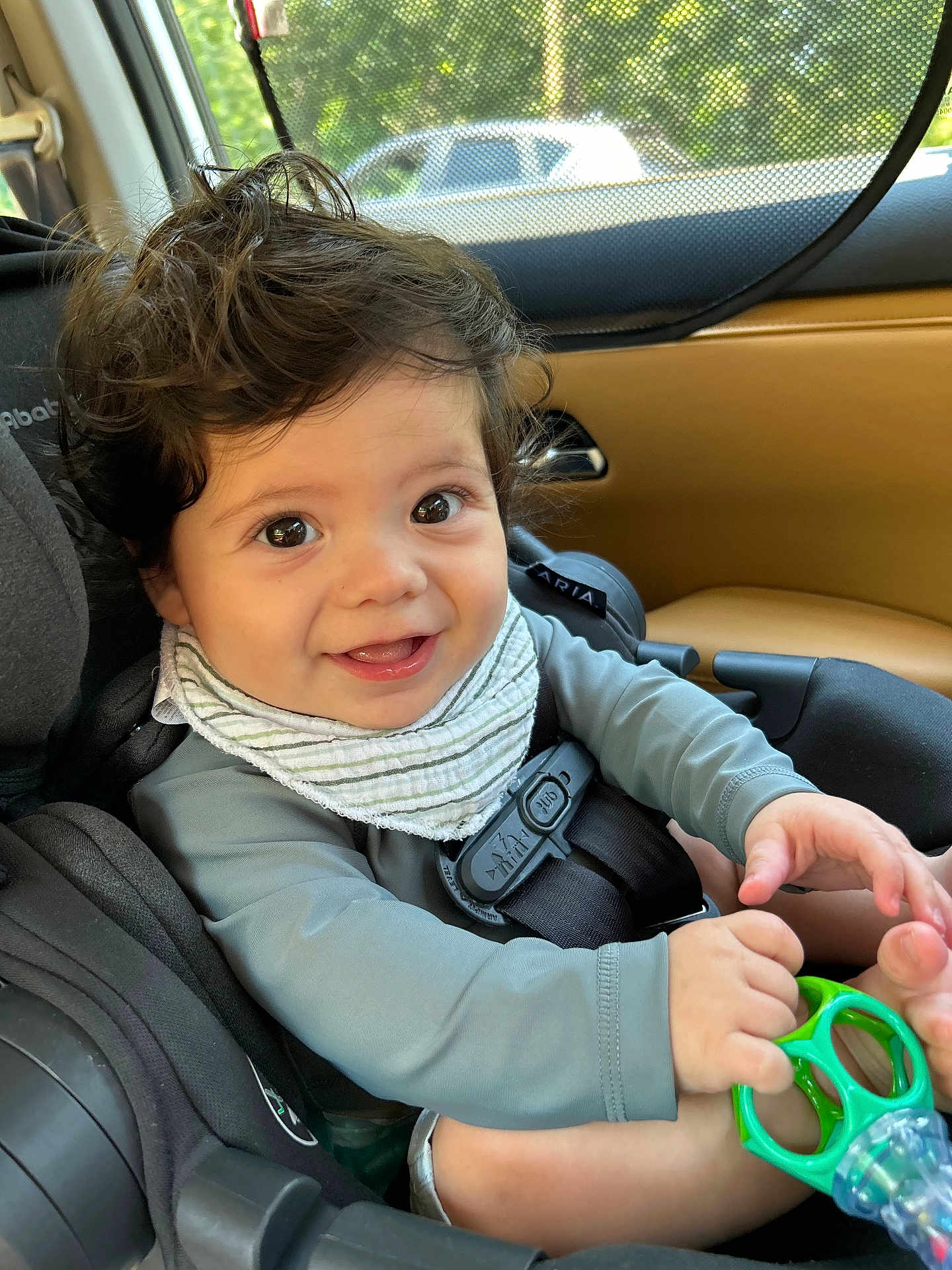 Mateo is registered to the contest to win money with this photo: baby, car_seat, child, smiling, toy, seatbelt, window, car_interior, happy, hair, face, hands, clothing, infant, safety, sunlight, seat, cute, portrait, young