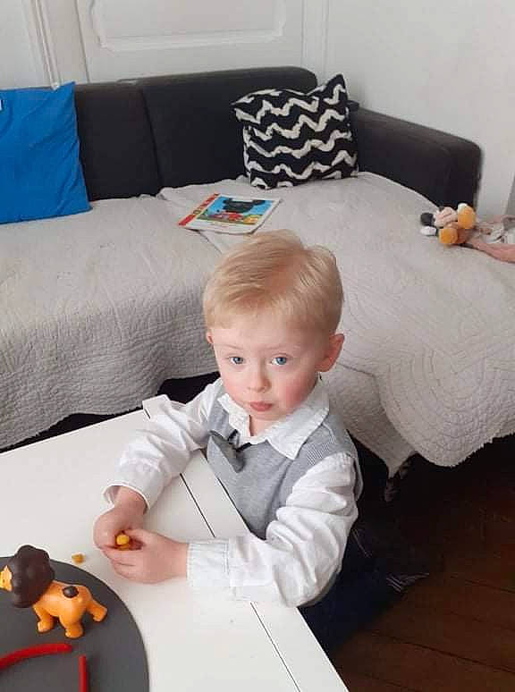 Angels a rejoint le concours — aidez-le/la à gagner de superbes lots ! baby, baby_toddler_clothing, child, comfort, couch, dress, flooring, furniture, linens, living_room, person, pillow, room, sitting, suit, table, textile, throw_pillow, tie, toddler